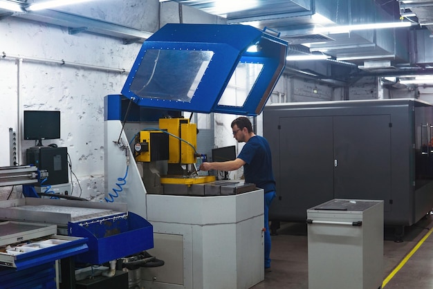 werknemer in de werkplaats regelt de werking van een metaalbewerkingsmachine