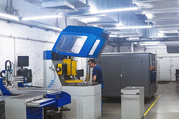 werknemer in de werkplaats regelt de werking van een metaalbewerkingsmachine