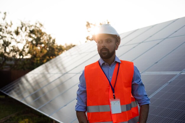 Werknemer in een vest en helm staat op een zonnestation