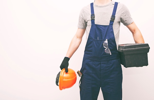 Werknemer in professionele uniform met toolbox in de hand op een grijze achtergrond