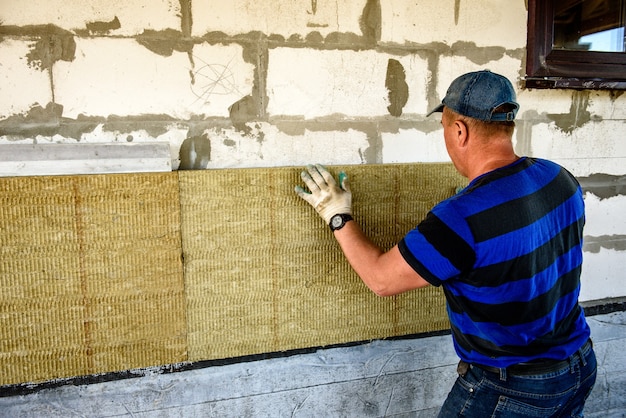 Werknemer isoleert het huis met platen van minerale wol. interne thermische isolatie van muren met minerale wol.