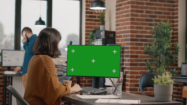 Werknemer kijken naar horizontaal groen scherm op computerscherm aan balie. Vrouw die monitor met geïsoleerde mockup-sjabloon en chromasleutel gebruikt om zakelijk project te plannen. Ondernemer aan het werk