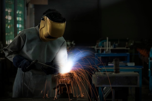 Werknemer lasser werk lassen staal in de industrie met veiligheid masker handschoenen en veiligheidsuitrusting.