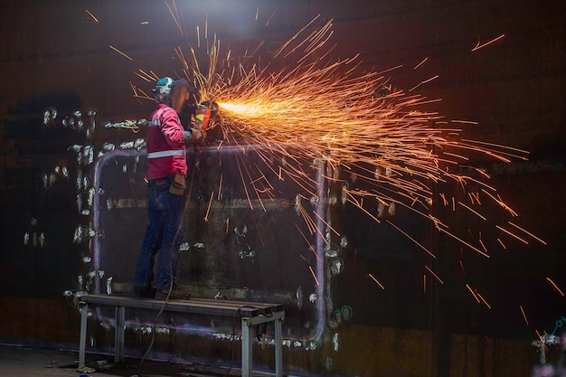 Werknemer met behulp van elektrisch wiel vonkslijpen op lasser metalen koolstofstaal deel schaalplaat binnen tank