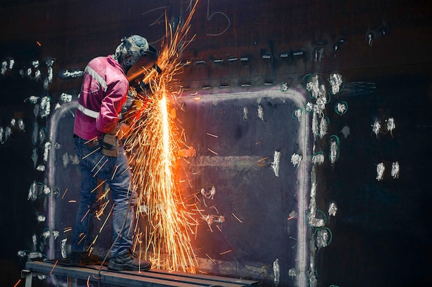 Werknemer met behulp van elektrisch wiel vonkslijpen op lasser metalen koolstofstaal deel schaalplaat binnen tank