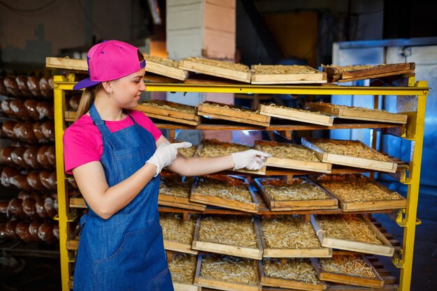 Werknemer met een doos pasta. Het meisje werkt aan de productie van spaghetti. Noedels maken. Pasta fabriek.