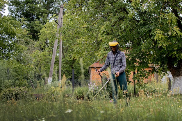 Werknemer met een gasmaaier in zijn handen, gras maaien voor het huis.