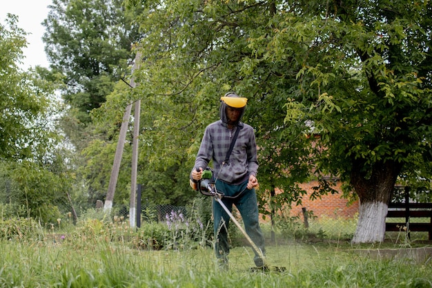 Werknemer met een gasmaaier in zijn handen, gras maaien voor het huis.