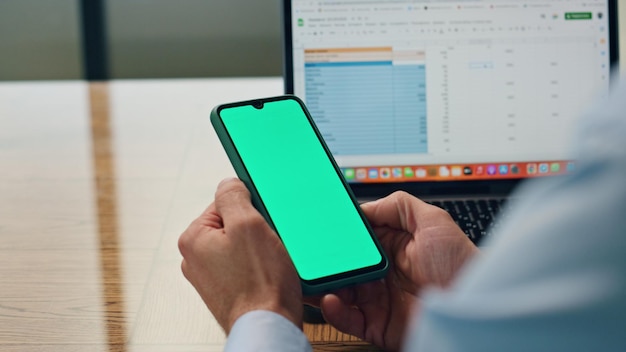 Werknemer met handen die een groene schermtelefoon vasthouden op kantoor close-up man die telefoon gebruikt