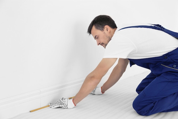 Werknemer met meetlint bereidt zich voor op het installeren van nieuwe tapijtvloeren