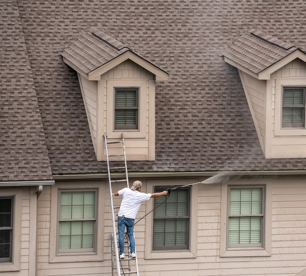 Werknemer op ladderdrukreiniging naar huis voorafgaand aan het schilderen