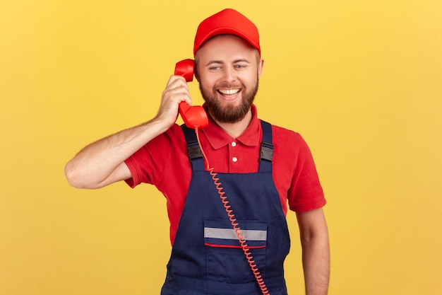 Foto werknemer praten op rode retro telefoon met klanten accepteert bestellingen professionele service-industrie