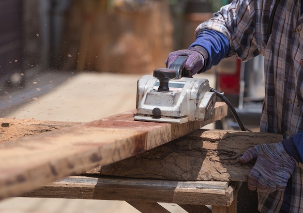 werknemer schaven een hout met een elektrisch vlak