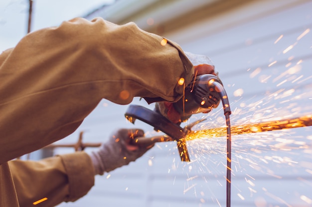 Foto werknemer snijdt een metalen buis met een molen