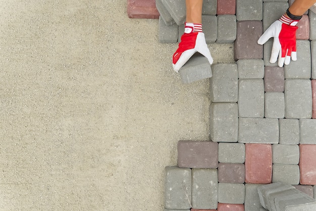 werknemer straatstenen te leggen. stenen bestrating, bouwvakker geplaveide rotsen op zand te leggen.