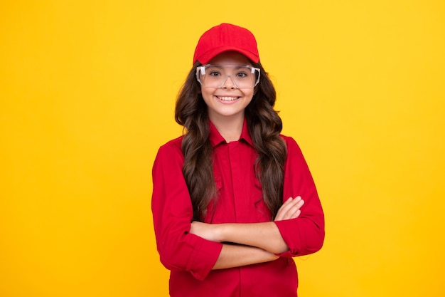 Werknemer tiener kind dragen overall rode dop en beschermen bril Studio shot portret geïsoleerd op gele achtergrond Blij gezicht positieve en lachende emoties van tiener meisje