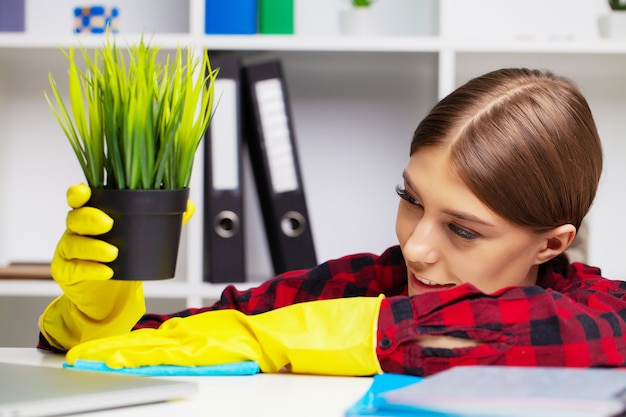 Werknemer van een schoonmaakbedrijf in overall en gele handschoenen maakt het kantoor schoon