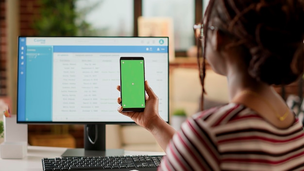 Werknemer van het bedrijf kijken naar smartphone-display met greenscreen, thuis werken op afstand. met behulp van geïsoleerde chromakey copyspace met lege mockup sjabloon en mobiele telefoon achtergrond.