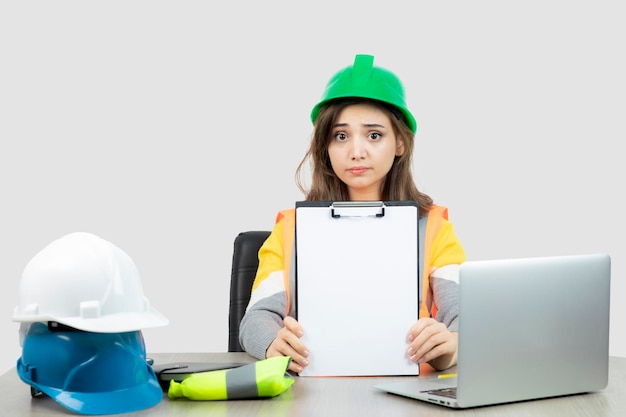 Werknemer vrouw in uniform zit aan de balie met laptop en klembord. Hoge kwaliteit foto