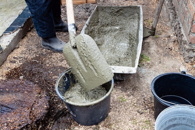 Werknemer zet beton in emmer met schop