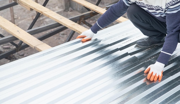 Werknemer zet de metalen tegels op het dak van een huis