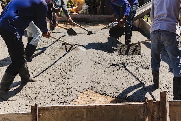 Werknemers bezinken en egaliseren het beton in de fundering