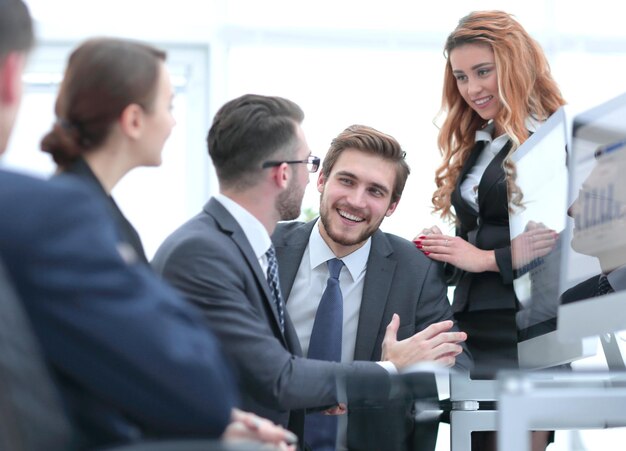 Werknemers die financiële grafieken bespreken die aan hun bureau op kantoor zitten