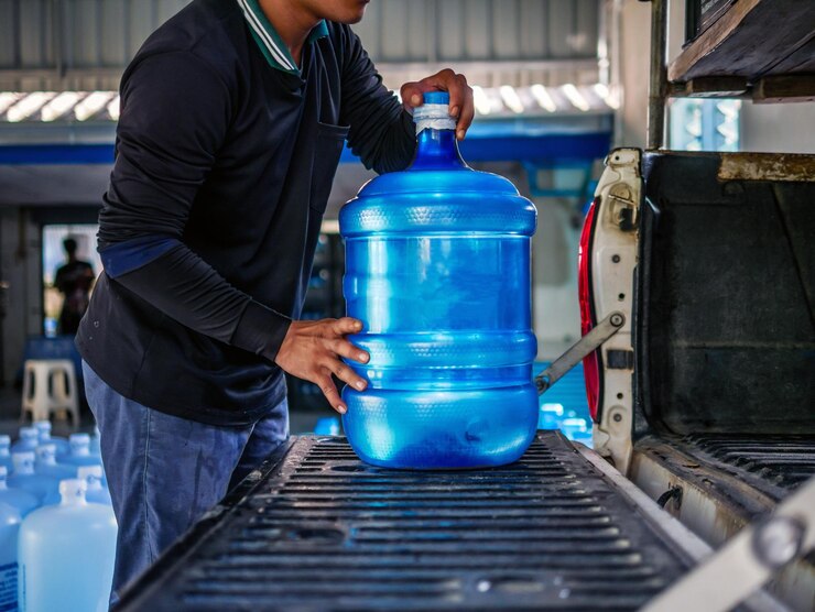 Werknemers die helder en schoon drinkwater in blauwe plastic gallons opheffen