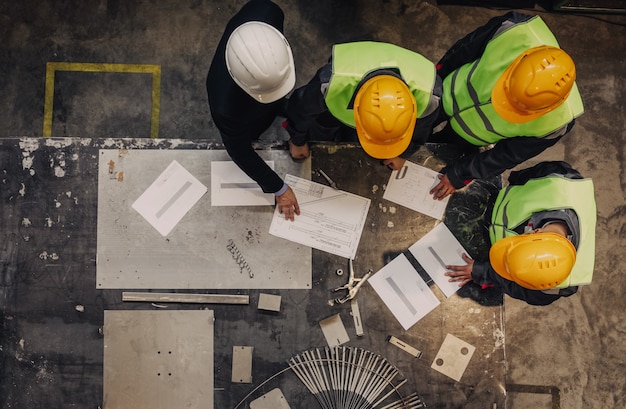 Werknemers en manager in veiligheidshelmen werken met documenten in de fabriek