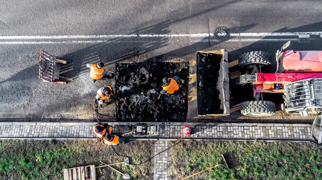Werknemers repareren het bovenaanzicht van de weg vanaf de drone