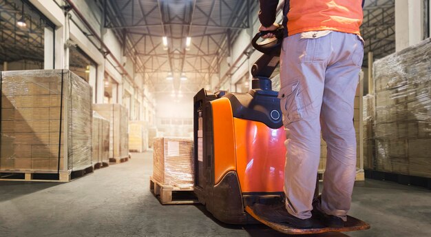 Werknemers rijden elektrische vorkheftruck Pallet Jack in magazijn lossen pakketdozen leveringen