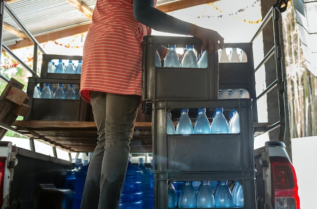 Foto werknemers tillen blauwe drinkwaterflessen in kratten achterin een klein transportwagentje