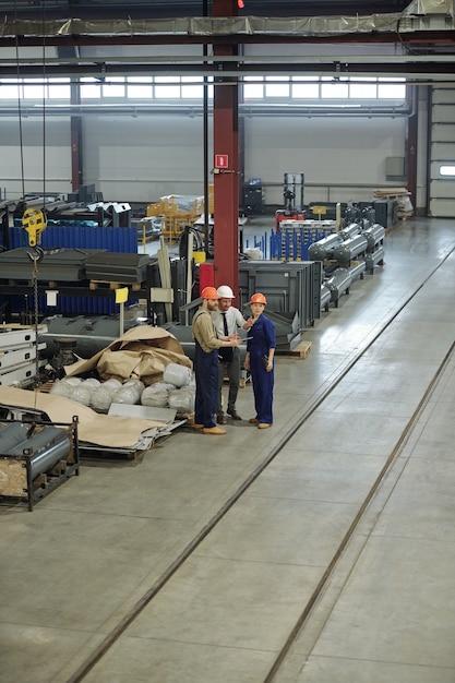 Foto werknemers van industriële installaties staan op luchttanks en bespreken hoeveelheid goederen in magazijn