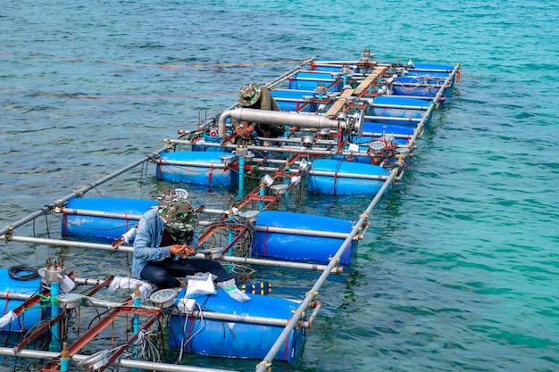 Werknemers vestigen en installeren de fonteinmachine van de waterleiding op het oppervlak van de zee