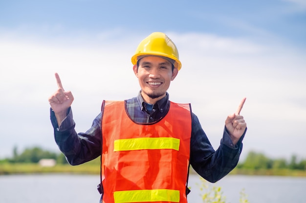 Werknemersbouwconcept Aziatische Werknemersbouwglimlach gelukkig staand buiten ter plaatse constructie