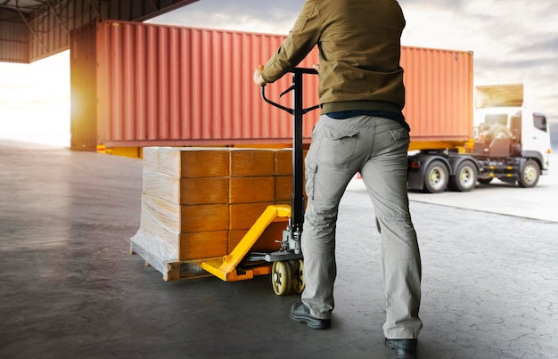 Werknemerskoerier die verpakkingsdozen op pallet lossen naar vrachtcontainer die vrachtvrachtwagens verschepen