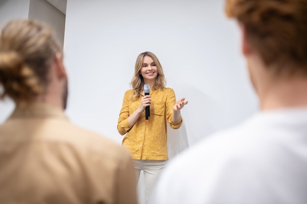 Foto werkplaats. blonde coach met een microfoon in gesprek met het publiek