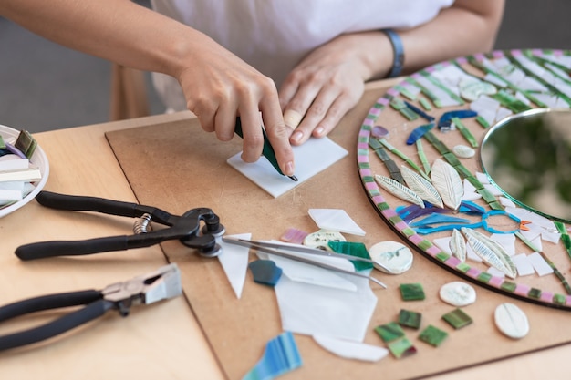 Werkplek van de handen van de mozaïekmeester die het gereedschap vasthoudt voor mozaïekdetails tijdens het maken van...