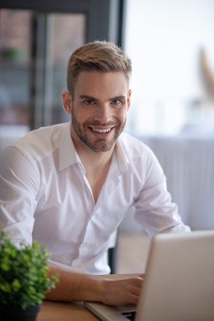 Werkproces. Een glimlachende knappe man aan het werk met zijn computer