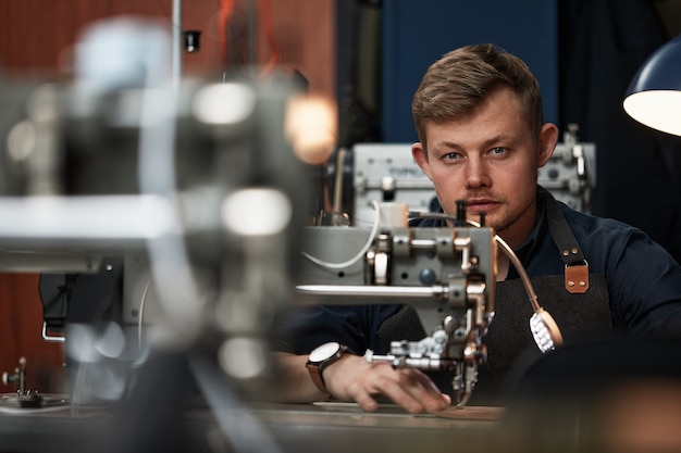 Werkproces van leer ambachtsman. Tanner of skinner naait leer op een speciale naaimachine, close-up. werknemer naaien op de naaimachine.