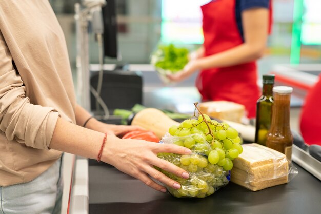 Werkroutine van vrouw die werkt als kassier in moderne supermarktkassa, horizontaal schot