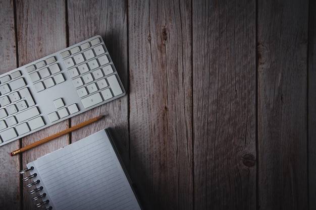 Werkruimte met computer toetsenbord notebook en potlood op houten achtergrond Bovenaanzicht Kopieer ruimte