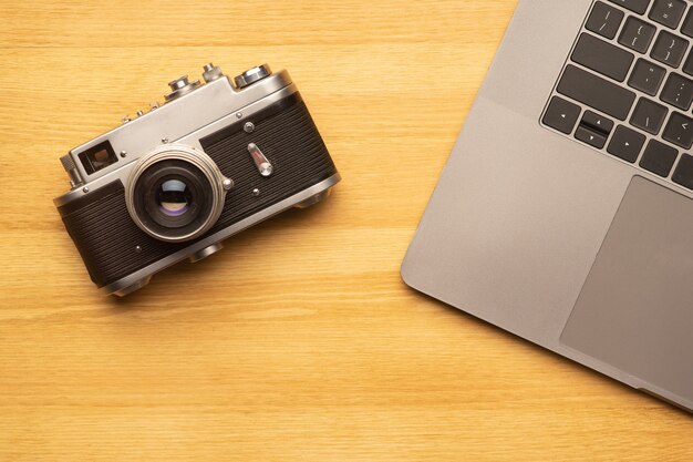 Werkruimte met laptopcomputer en camera op houten tafel. Bovenaanzicht