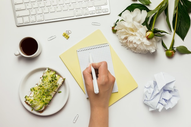 Werkruimte met lege toetsenbord, vrouwelijke hand, notebook, kantoorbenodigdheden