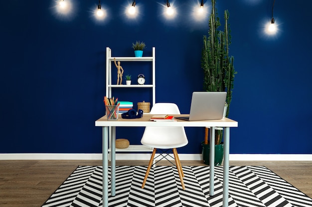 Werktafel met laptop tegen blauwe muur in moderne flat