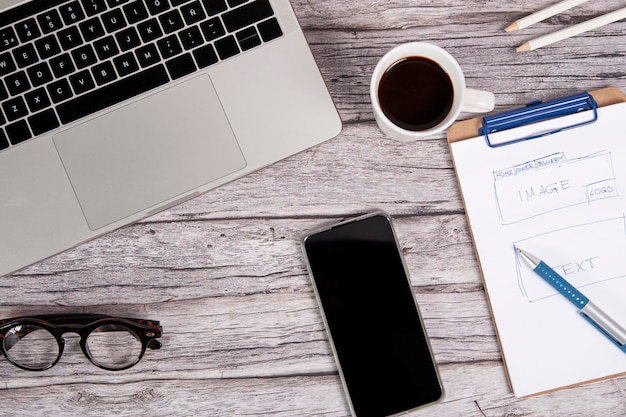 Werktafel voor websiteontwerper met laptop en een smartphone op een houten bureau