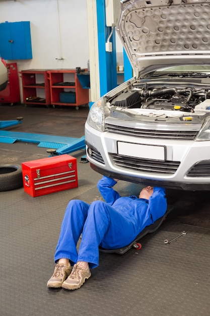 Werktuigkundige die en onder auto liggen kijken