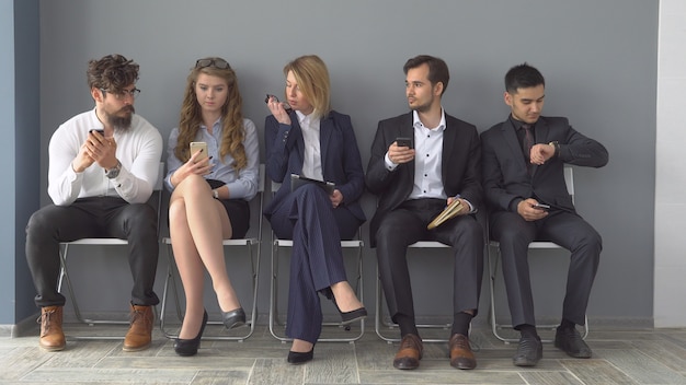 Werving voor het bedrijf. Jonge sollicitanten wachten op een interview. een groep jongeren verveelde zich te wachten op een sollicitatiegesprek.