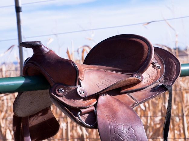 Western horse saddle on metal fence.