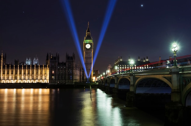 Foto westminster abbey en big ben over de theems in londen met reflectie op de rivier 's nachts. monument voor de tweede wereldoorlog